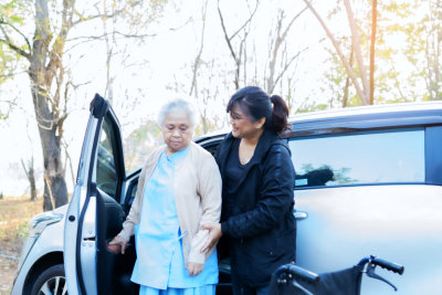 aide assisting an elderly woman getting off of the car