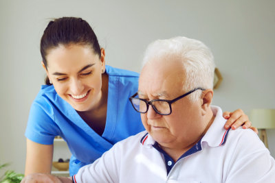 aide smiling while assisting the elderly man