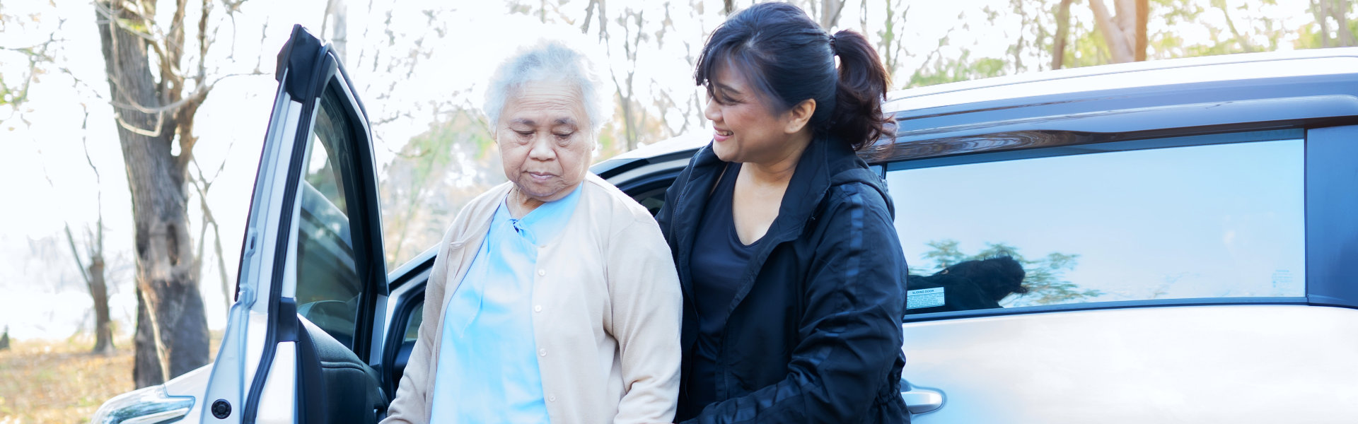 aide assisting an elderly woman getting off of the car