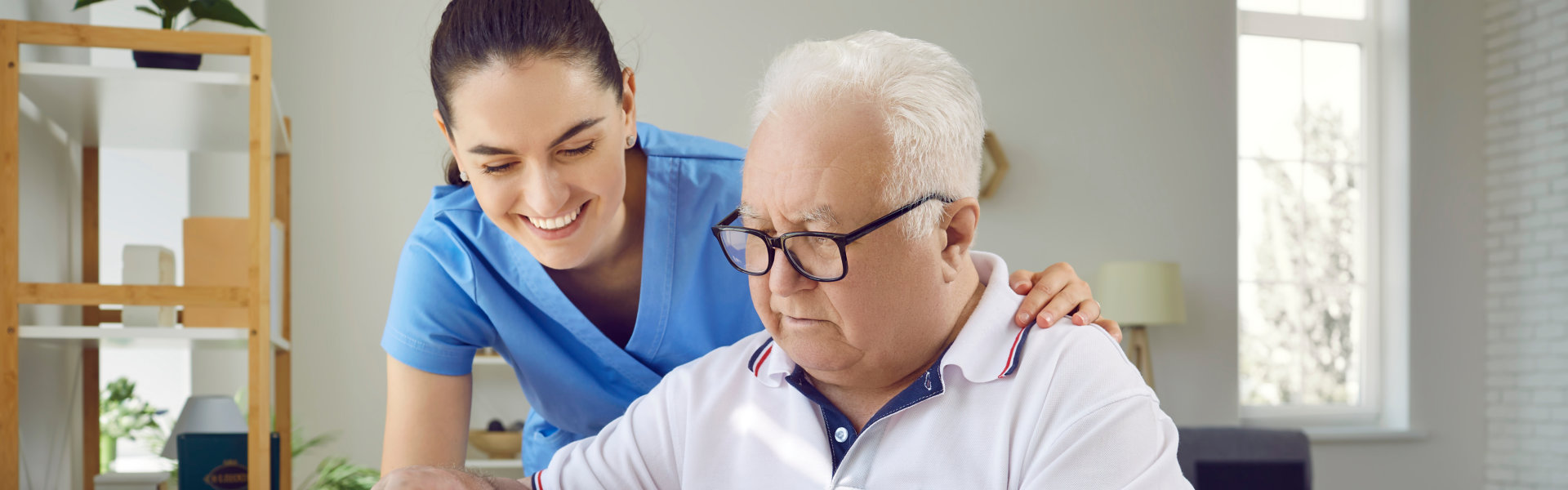 aide smiling while assisting the elderly man